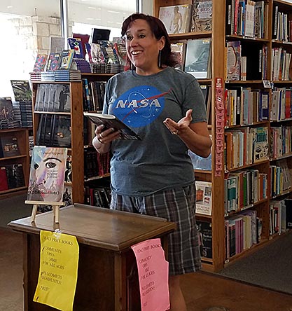 photo of Janet Kuypers, with her book “(pheromemes) 2015-2017 show poems” live