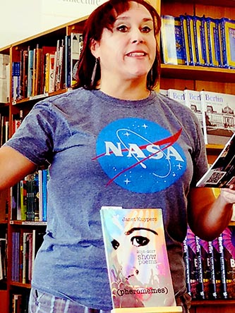 photo of Janet Kuypers, with her book “(pheromemes) 2015-2017 show poems” live