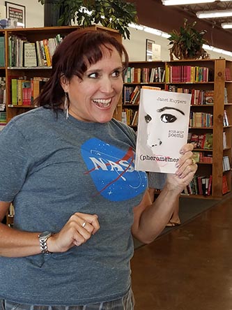 photo of Janet Kuypers, with her book “(pheromemes) 2015-2017 poems” live