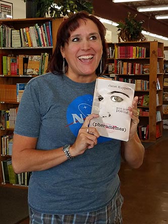 photo of Janet Kuypers, with her book “(pheromemes) 2015-2017 poems” live