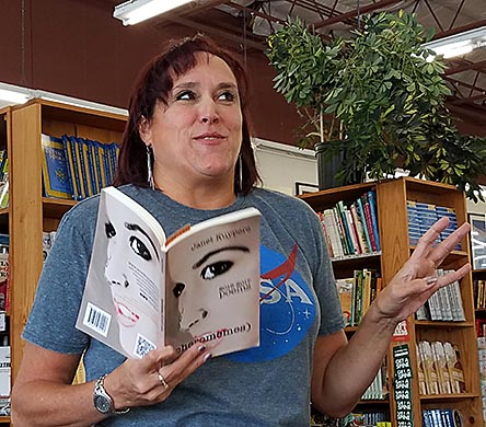 photo of Janet Kuypers, with her book “(pheromemes) 2015-2017 poems” live