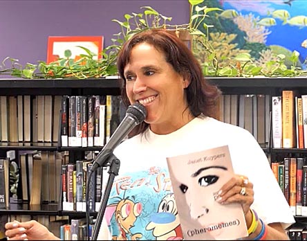 video still of Janet Kuypers reading from her book “(pheromemes) 2015-2017 poems” live